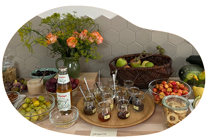 Ein Frühstücksbuffet mit vielen frischen Früchte. Das Buffet ist dekoriert mit einem Blumenstrauß, Kürbissen und Zucchini.