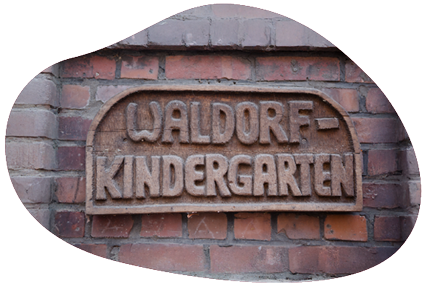 an einer Backsteinwand ist ein Holzschild, auf dem steht: Waldorfkindergarten